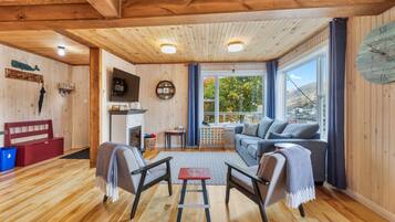 A cozy room with a fireplace, a sofa, two chairs, and a large window with a view.
