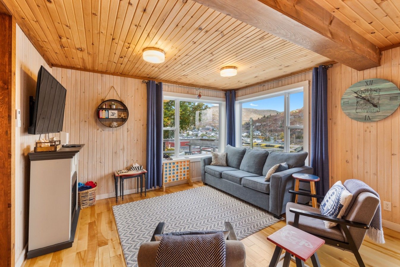 Una habitación acogedora con sofá, una mesa, una silla, televisor y un ventanal con vistas.