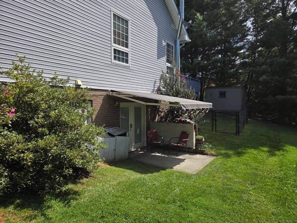 A residential house with a covered patio, a fenced yard, and a small shed.