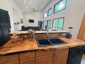 A kitchen with a wooden countertop, a sink, a blender, and a dishwasher.
