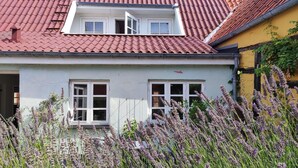 Ein zweistöckiges Haus mit rotem Ziegeldach, weißen Wänden und einem kleinen Balkon.