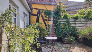 Ein Innenhof mit einem Ziegeldach, einem kleinen runden Tisch und zwei Stühlen.