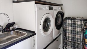 Ein kleiner Waschraum mit Waschmaschine, Trockner und Wäscheständer.