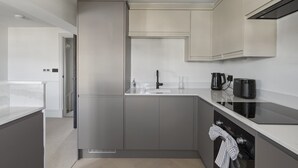 A modern kitchen with a built-in oven, a coffee maker, and a toaster on the countertop. - Beautiful Apartment on Pier, Sea Views & Parking (West Bay)