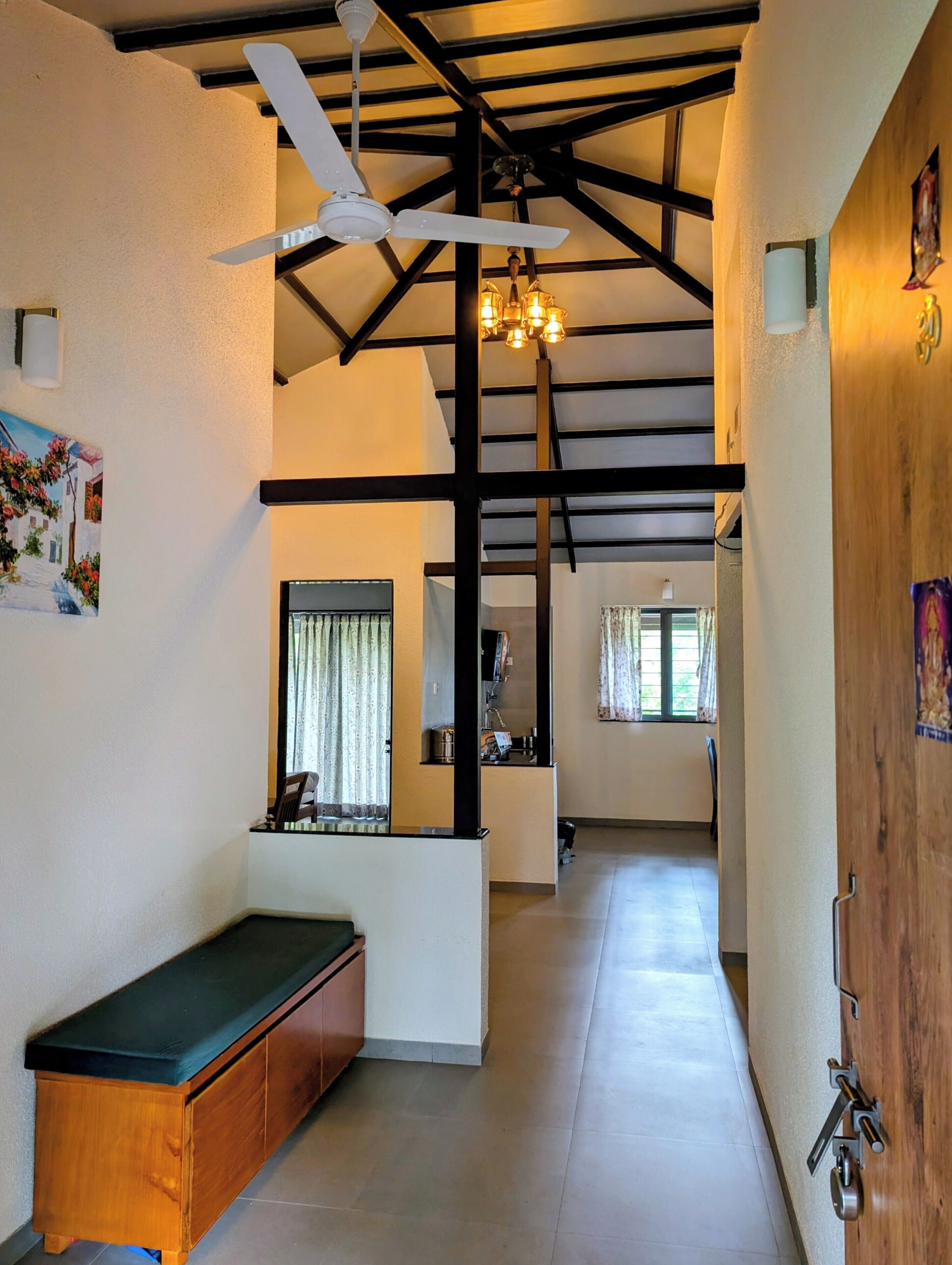A spacious hallway with a ceiling fan, a bench, and a wooden door.