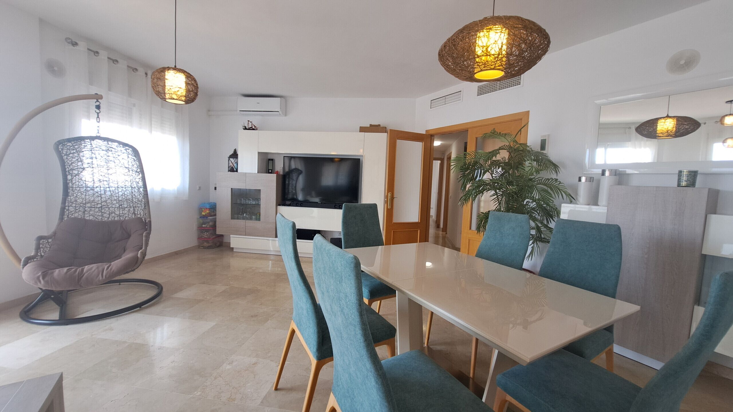 A modern living space with a dining area, a television, and a plant.
