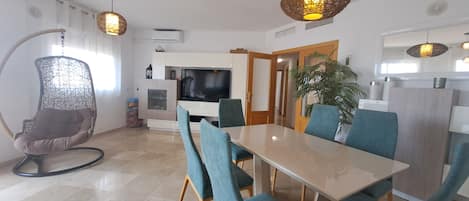 A modern living space with a dining area, a television, and a plant.