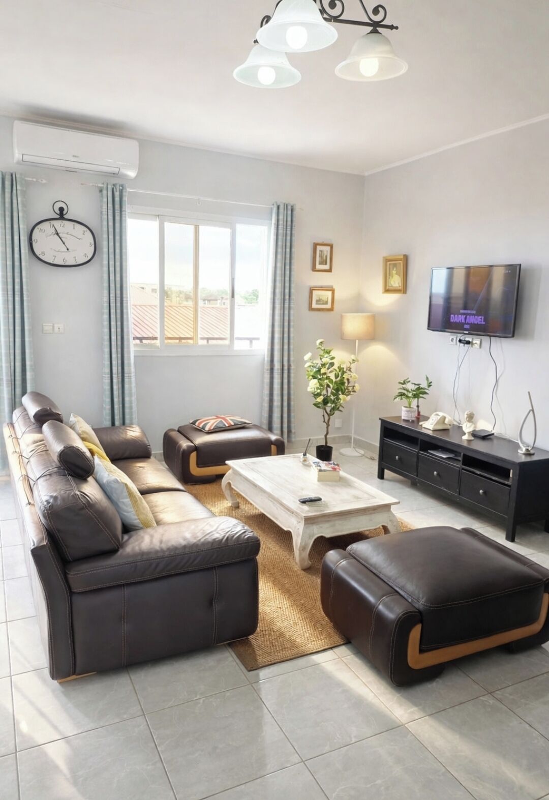 Ein modernes Wohnzimmer mit einer Sofagarnitur, einem Couchtisch, einem Fernseher und einer Wanduhr.