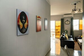 A modern living room with a sofa, a dining area with a table, and artwork on the walls.