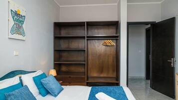 A bedroom with a bed, a wardrobe, a door, and a wall-mounted light switch.