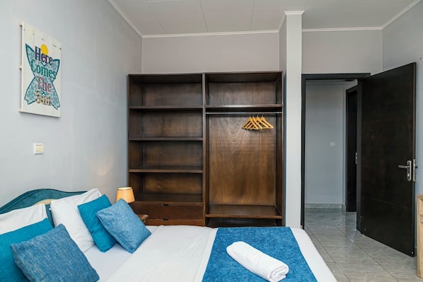 A bedroom with a bed, a wardrobe, a door, and a wall-mounted light switch.