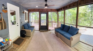A covered porch with wicker furniture, a ceiling fan, and a view of the outdoors.