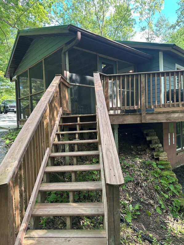 A wooden staircase leading to a covered outdoor area with a metal railing.