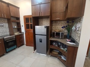A kitchen with wooden cabinets, a stainless steel refrigerator, a microwave, and a stove.