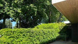 Un sendero pavimentado que conduce a un edificio con techo de madera y una cerca metálica.
