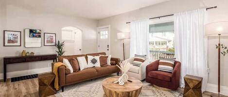 A living room with a brown sofa, a round coffee table, and a patterned rug.