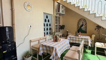 Eine Terrasse im Freien mit zwei Tischen und Stühlen, einem Wasserspender und einer dekorativen Wand.