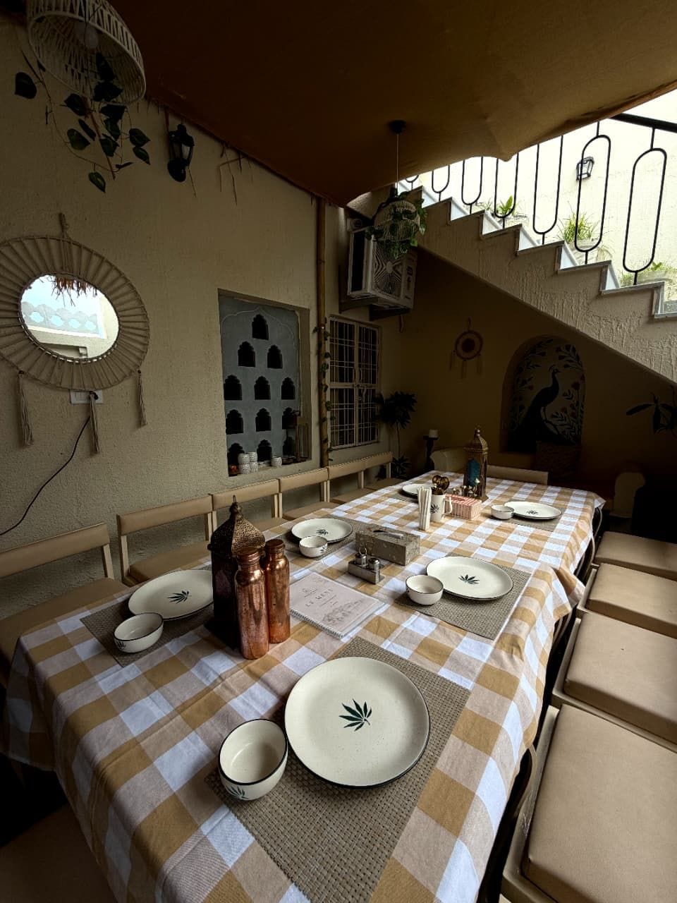 Un comedor con manteles a cuadros, una mesa larga y diferentes platos y cubiertos.