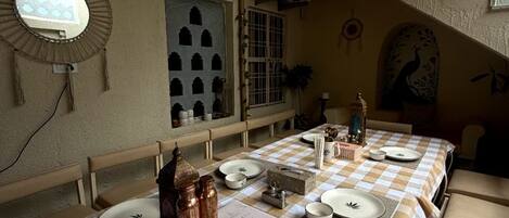 Un comedor con manteles a cuadros, una mesa larga y diferentes platos y cubiertos.