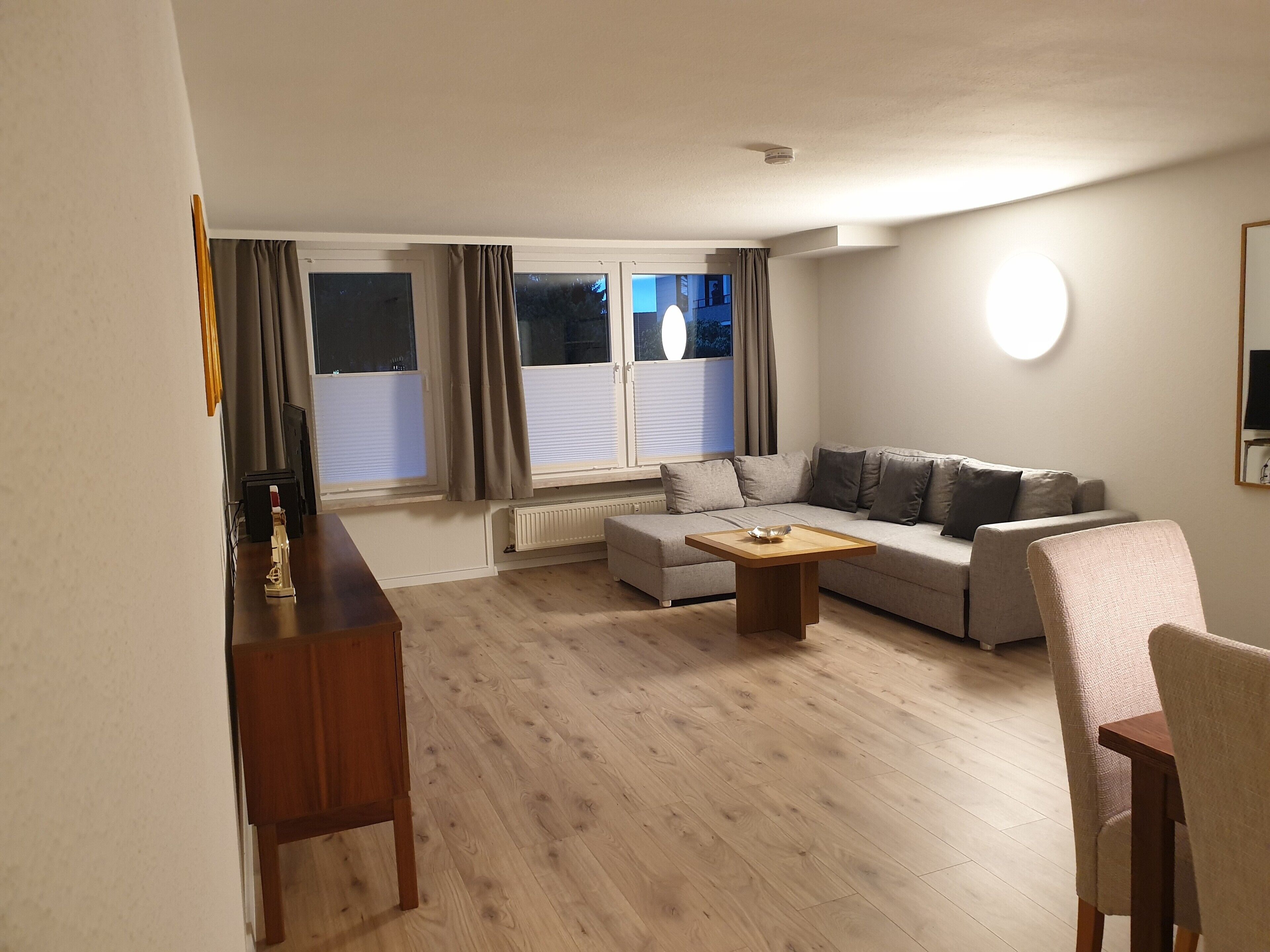 A living room with a sofa, a coffee table, a dining table, and a chair.