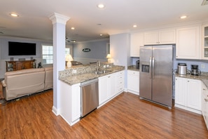 A modern kitchen with granite countertops, stainless steel appliances, and white cabinetry. - 5 BR Beach House with a Large Private Pool! Beach Buzz (Surfside Beach)