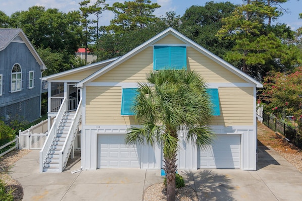 A two-story house with a front porch, a garage, and a palm tree in the front yard. - 5 BR Beach House with a Large Private Pool! Beach Buzz (Surfside Beach)