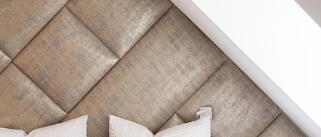 A bedroom with a sloped ceiling, a bed with white bedding, and a headboard made of wooden panels.