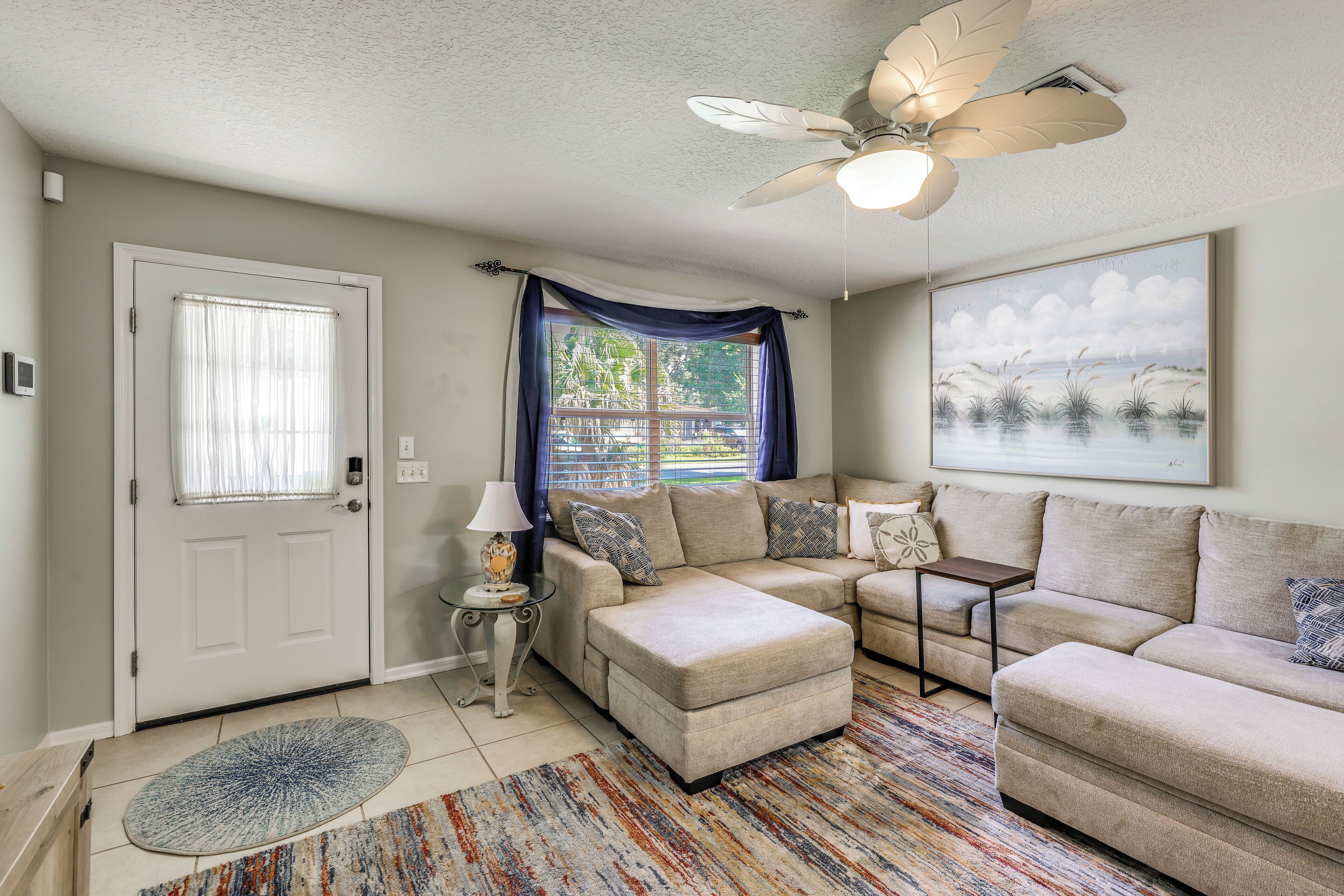 A living room with a ceiling fan, a sofa, a coffee table, and a painting on the wall.