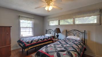 A bedroom with two beds, a ceiling fan, a window with a view, and a wooden wardrobe.