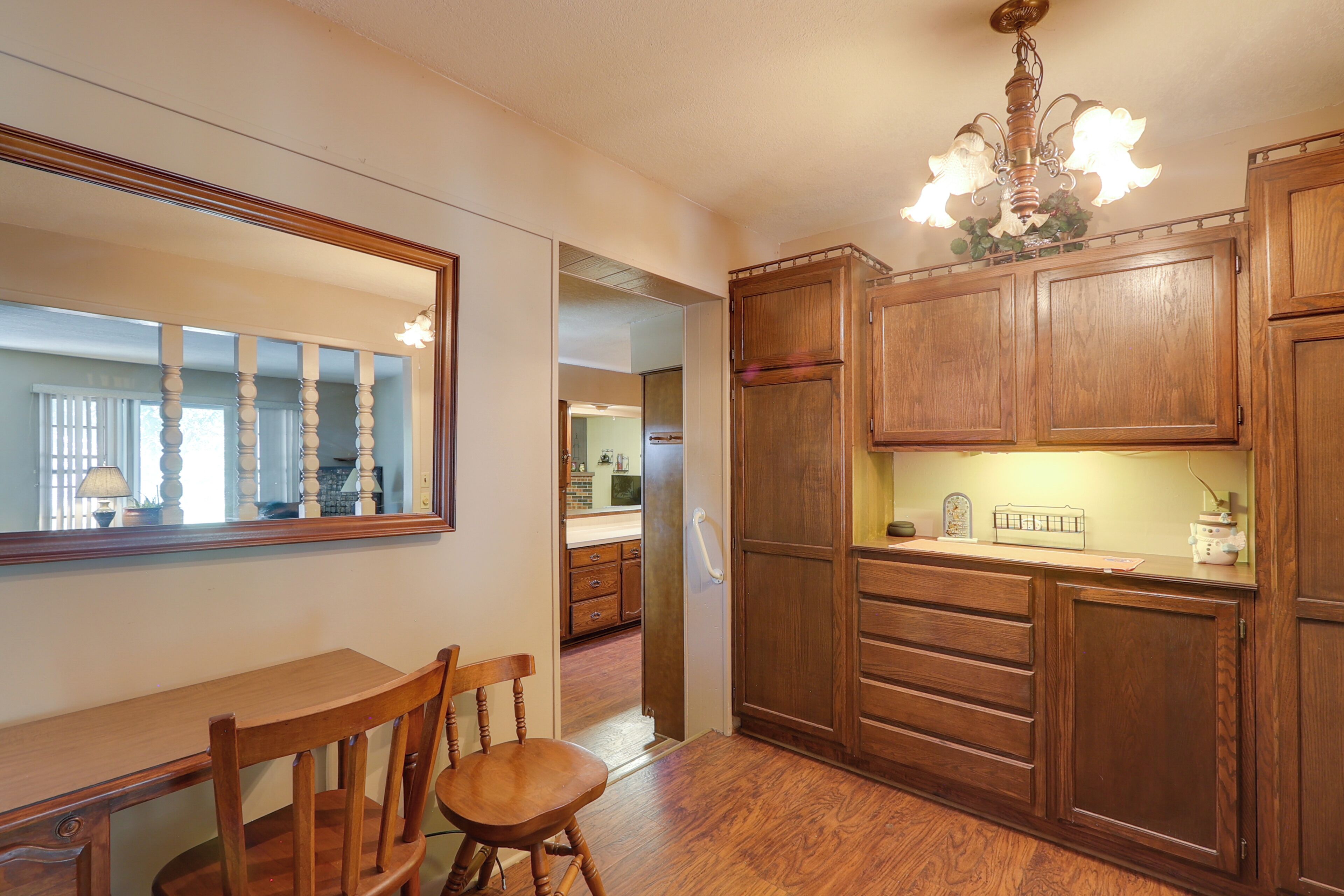 A wooden dining area with a chair, a table, and a mirror on the wall.