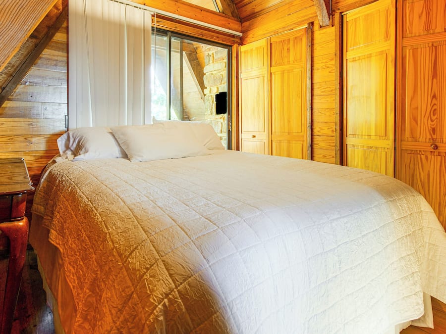 Ein Schlafzimmer mit einem großen Bett, Holzwänden und einem Fenster.