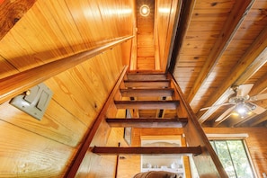 A wooden interior with a staircase, a ceiling fan, and a window.