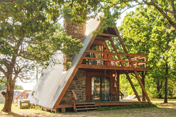 Una cabaña con techo inclinado, vigas de madera y chimenea de piedra.