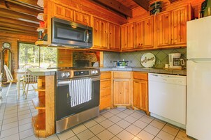 Una cocina con armarios de madera, horno de acero inoxidable, microondas, cafetera y lavavajillas.