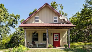 A two-story house with a red door, a covered porch, and satellite dishes.