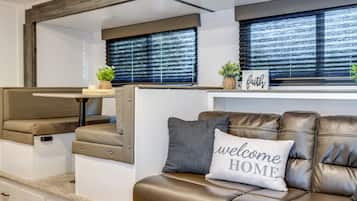 A modern RV interior with a sofa, a small table, and a bench.