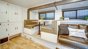 A compact RV interior with a kitchenette, seating area, and storage cabinets.