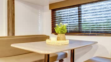 A compact living space with a bench, a small table, and a window with blinds.