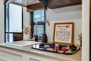 A compact kitchen with a sink, a framed sign, and a window with blinds.