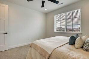 Ein Schlafzimmer mit Bett, einem Fenster mit Jalousien, einem Deckenventilator und einer Tür.