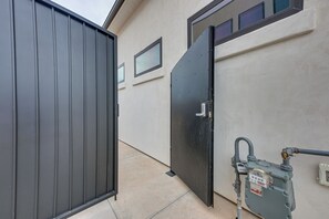 A gated entrance with a metal gate and a door, a concrete pathway, and a utility meter on the right. - Resort-style St George Casita w/ Lagoon Access (St. George)