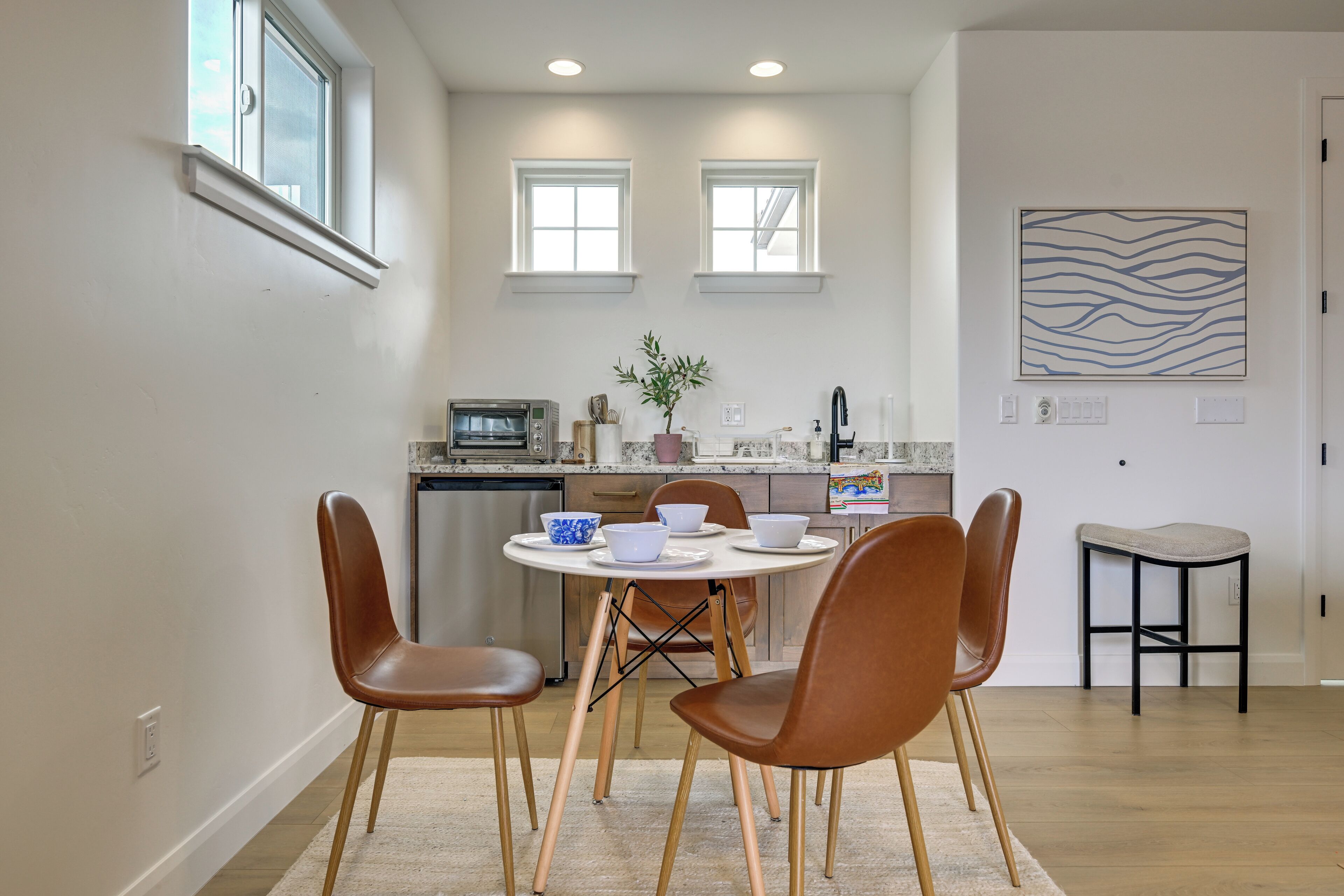 Una cocina moderna con comedor, que presenta una mesa redonda con sillas, horno empotrado y encimera con pileta.
