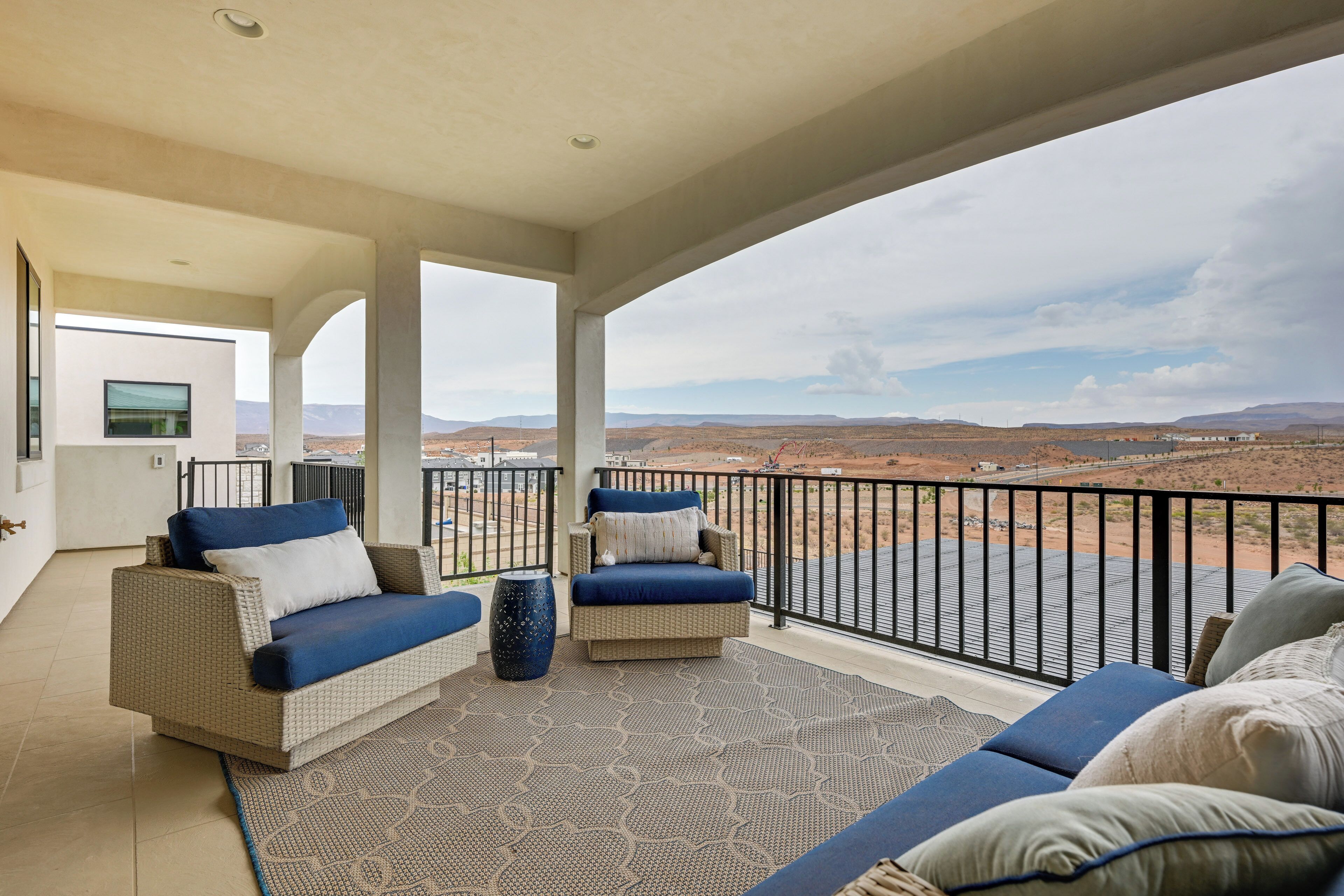 A balcony with wicker furniture, a patterned rug, and a view of a desert landscape.