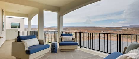 A balcony with wicker furniture, a patterned rug, and a view of a desert landscape.