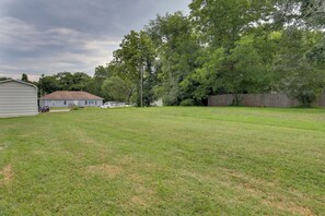 A residential backyard with a house, a fenced area, and a grassy lawn.