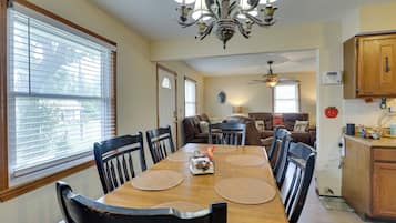 A dining area with a wooden table, black chairs, and a chandelier.