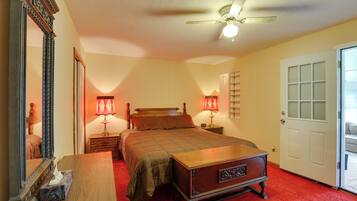 A bedroom with a bed, bedside lamps, a dresser, a mirror, and a ceiling fan.