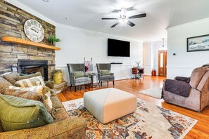 A living room with a stone fireplace, a flat-screen TV, and a ceiling fan. - 8 Mi to Dtwn Mt Airy: Mtn-view North Carolina Home (Ararat)
