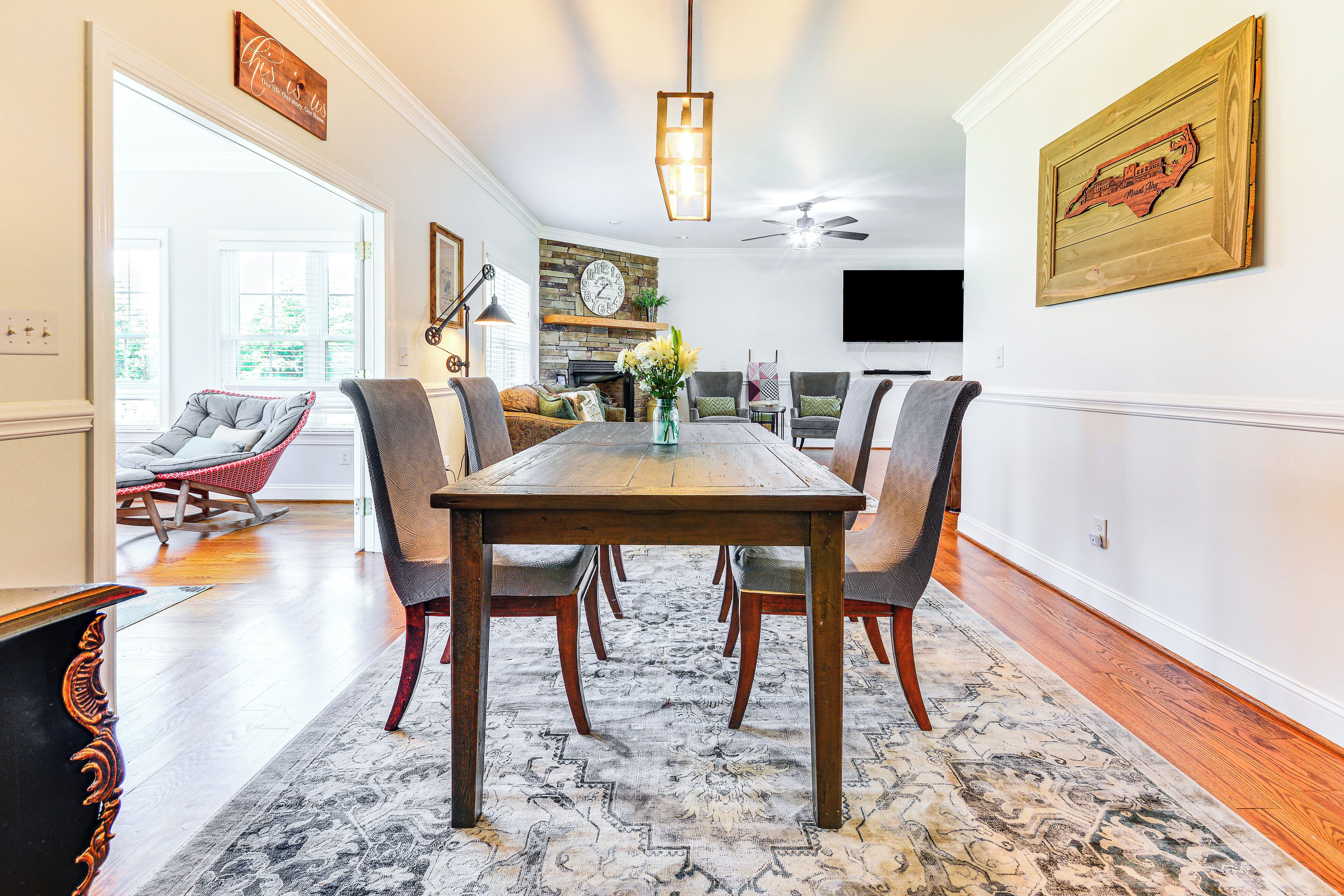 A dining area with a wooden table, chairs, and a patterned rug.
