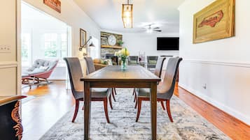 A dining area with a wooden table, chairs, and a patterned rug.